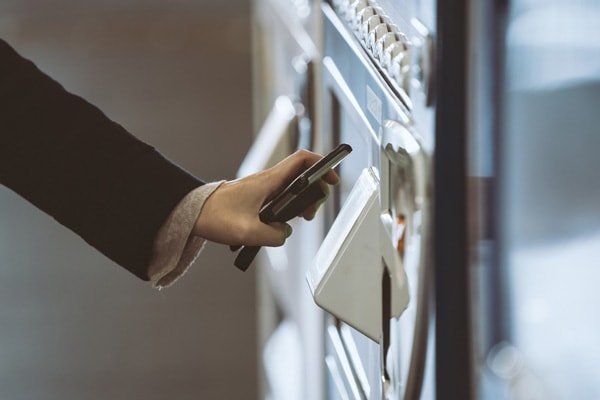 Employee using cellphone to pay for vending machine purchase.